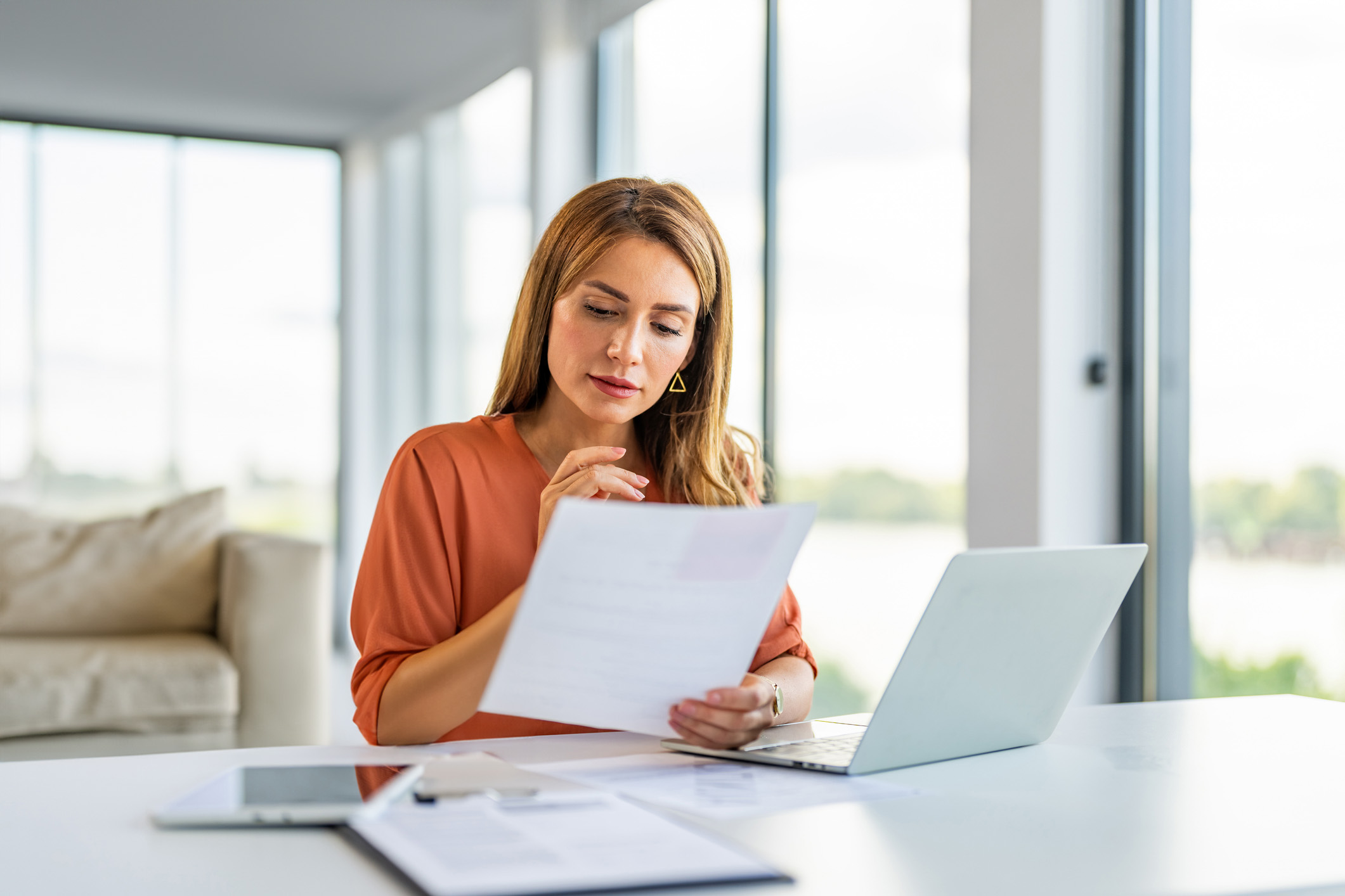 Woman Reading Paper w Laptop family room